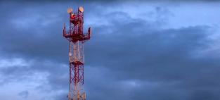 Screenshot from a UTS video of a mobile phone tower against a cloudy sky