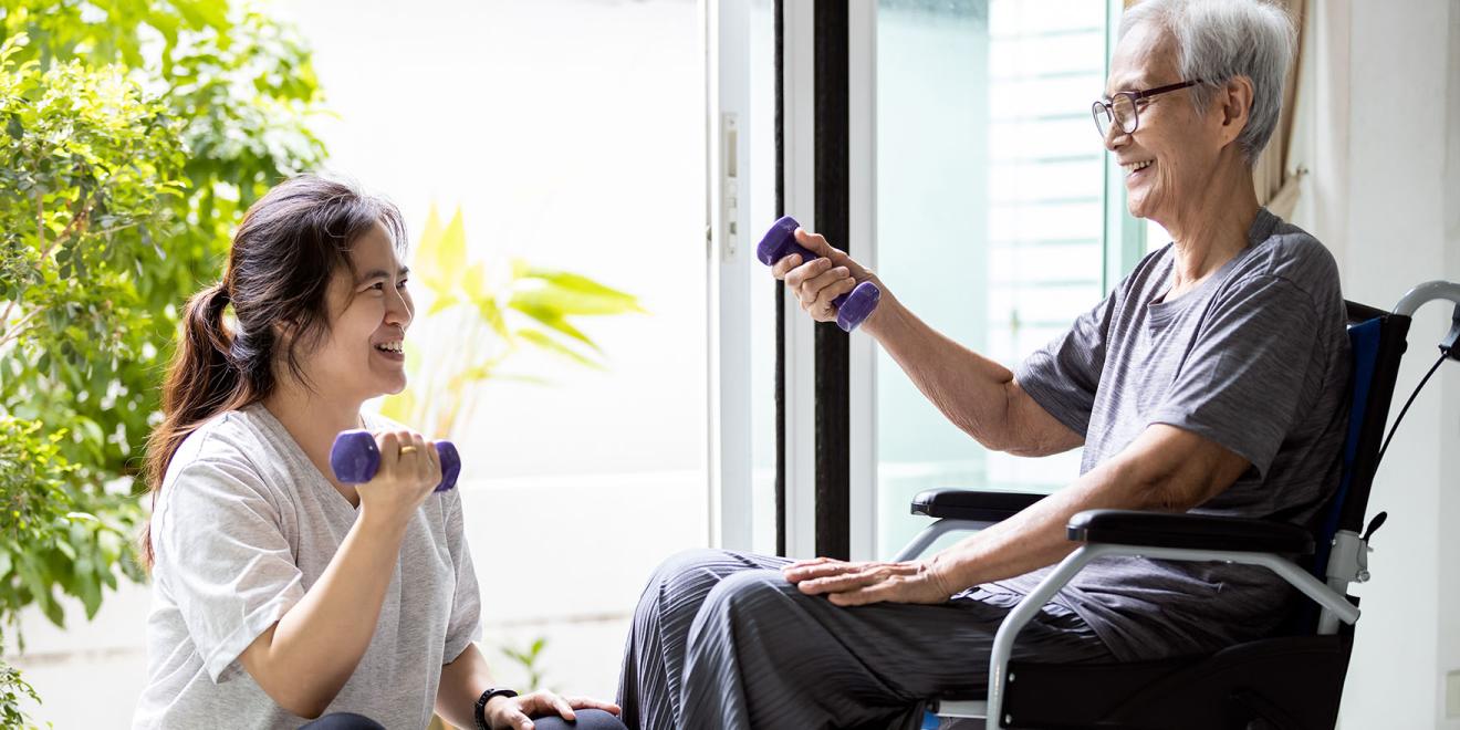 Caregiver doing physical therapy with elderly person