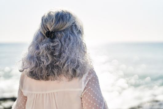 Woman looks out at the ocean. Image: Adobe Stock