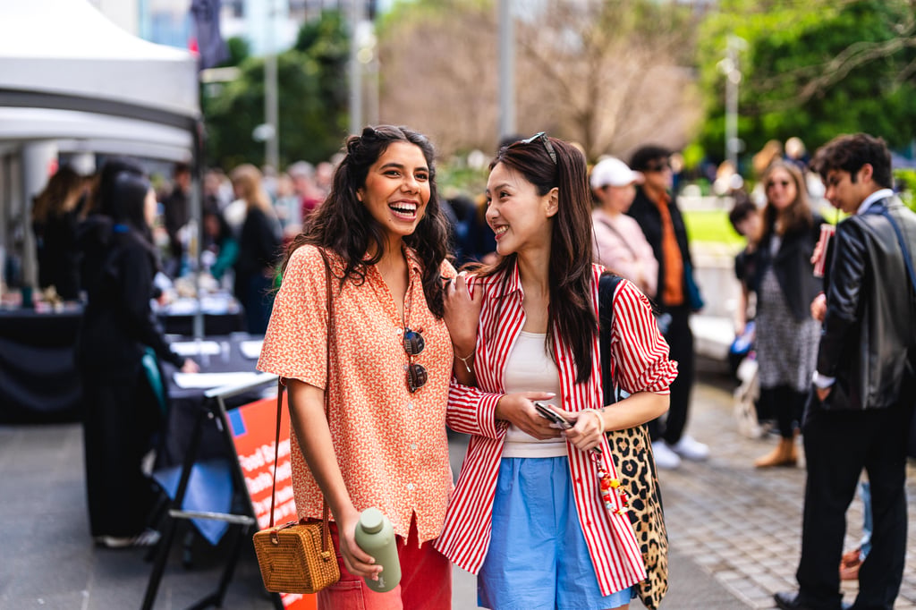 Two UTS prospective students stand side by side at university Open Day event, enjoying the atmosphere and engaging with the surrounding crowd.