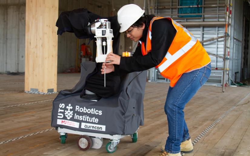 A researcher sends commands to a robot on a construction site.