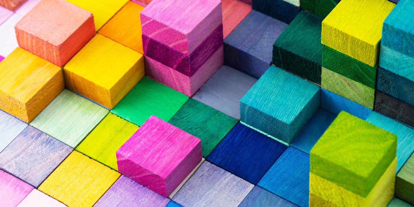 An assortment of wooden building blocks in a variety of bright colours.