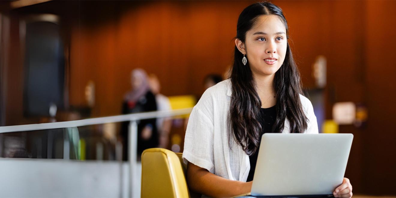 A student sitting with her computer in the foyer of UTS building 11