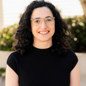 Woman with dark hair and glasses smiling