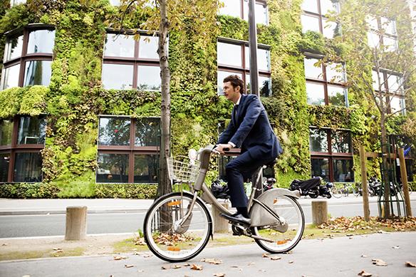 man riding bike past vertical garden