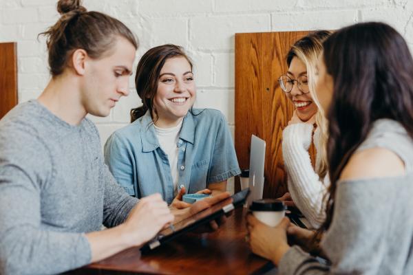 Students sitting at a table studying and looking happy. 