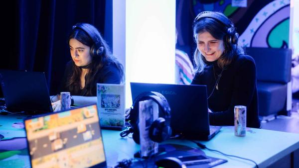 Two young women wearing earphones and interacting with computers at a SXSW event