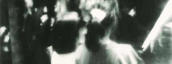 2 children standing side by side, with their backs to the camera.
