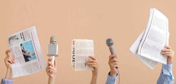 hands with microphones and newspapers on beige background