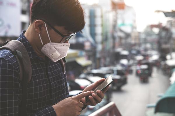 man with medical face mask using the phone to search for news