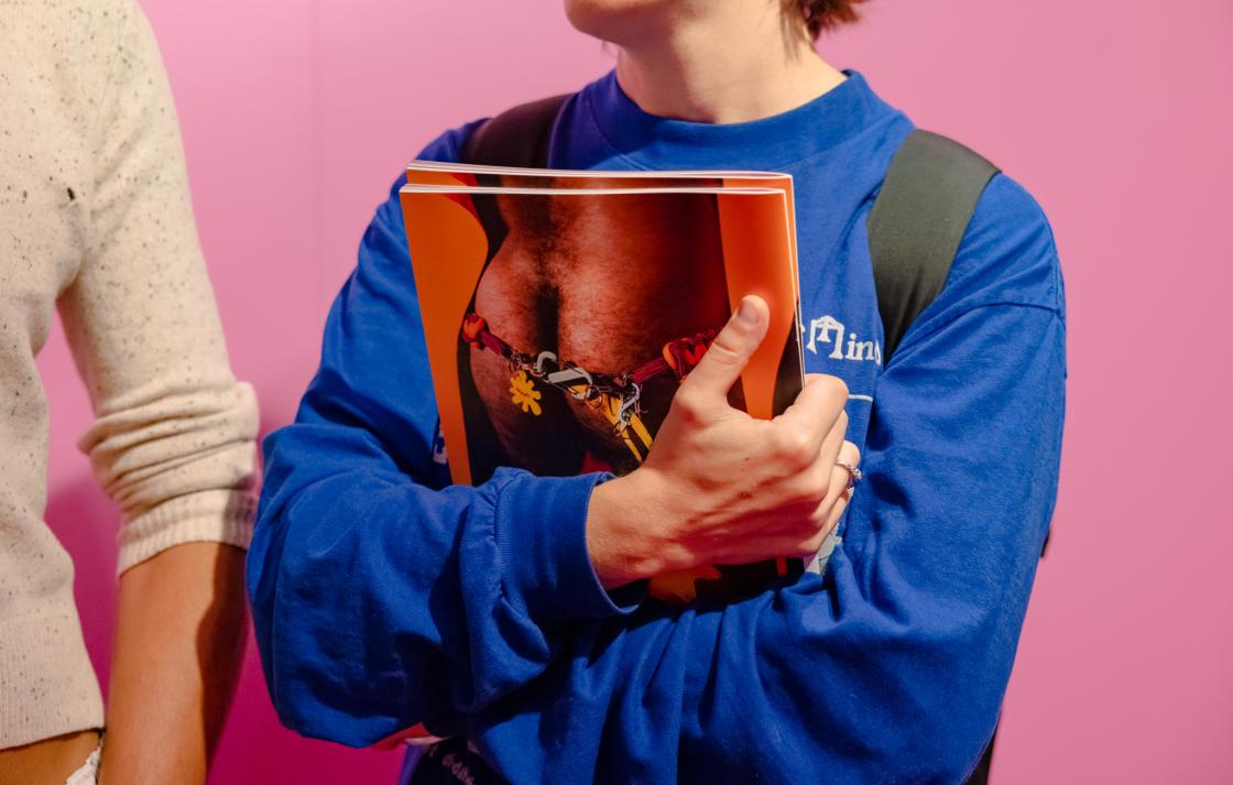A person in a blue jumper holds a book with a bum on the back cover