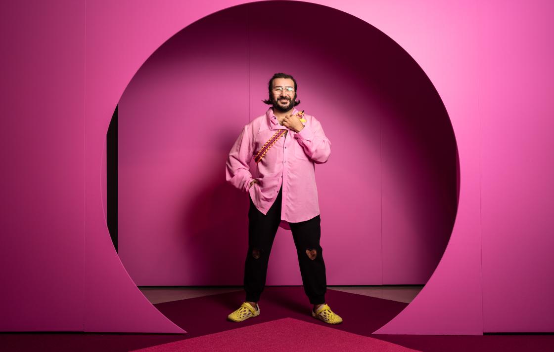 A person in a pink shirt stands in round doorway painted pink