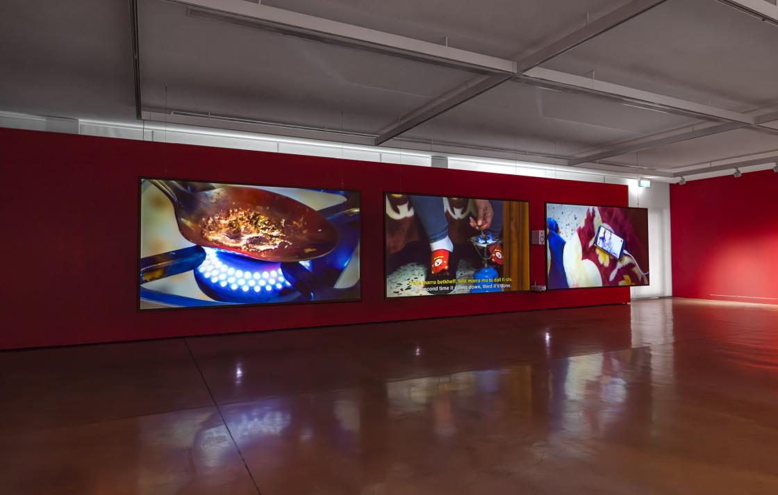 A three channel video work in a gallery with red walls 