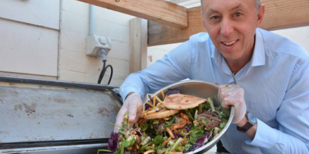 A man tips a bowl of food rubbish into an air drying machine