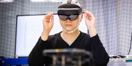 PhD student, Daniel Leong uses augmented reality (wears dark glasses and a headset) to control a BCI-enabled robot (faded in the foreground)