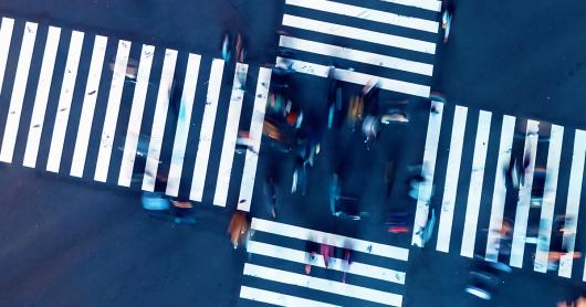 An aerial image of people walking across a pedestrian crossing at an intersection 