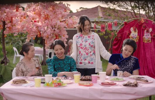 Image of four women at lunch outside. They are smiling and talking. The image has a lot of pink elements in it.