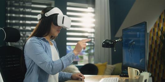 Woman sitting at desk and using VR headset to work