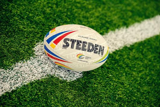 Stock picture of a Steeden Rugby League ball placed on a football field line marking