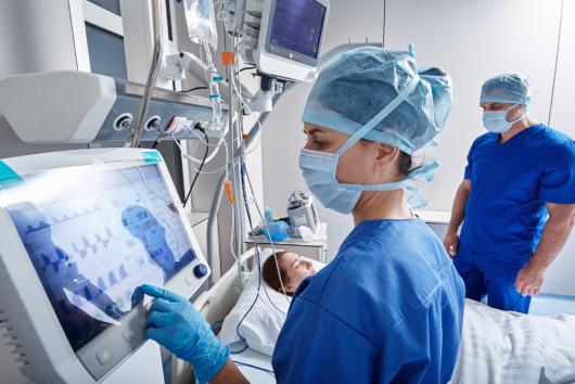 Hospital nurses checking on woman patient at intensive care unit.