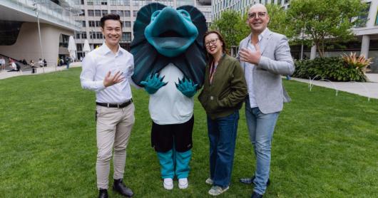 Three people and Lenny the Lizard holding their hand up