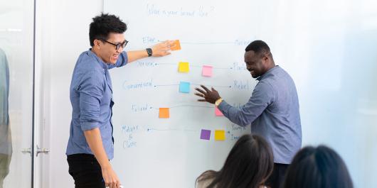 Students brainstorming ideas together on whiteboard