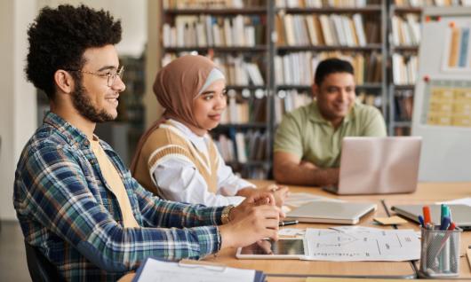 Migrant students studying together at a table. Adobe Stock