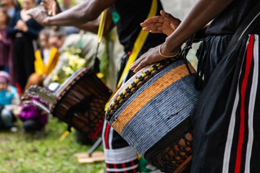 Closeup midsection of two artist performing traditional colorful string wrapped african djembe drums while standing in city during event By Valmedia