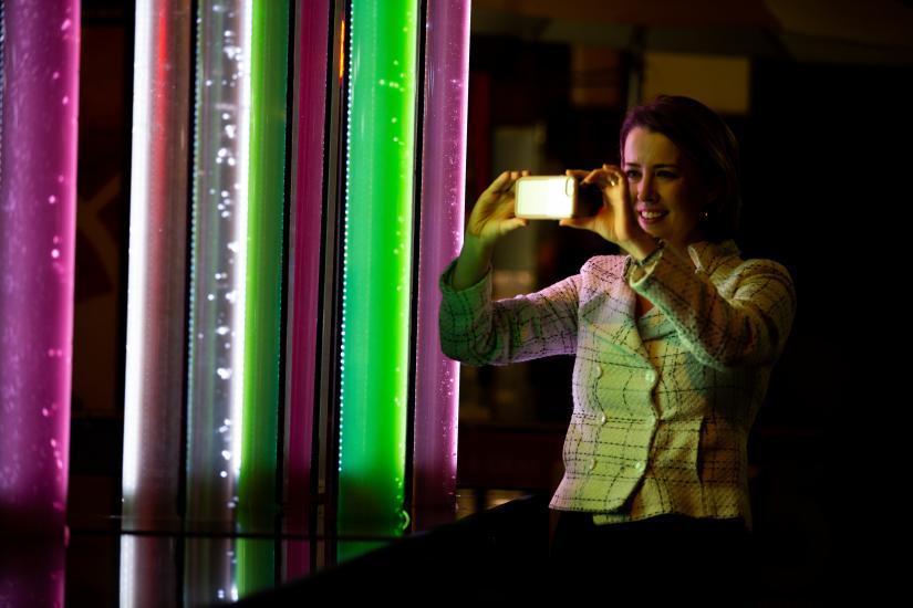 A woman photographing the algae tubes at Vivid Light festival