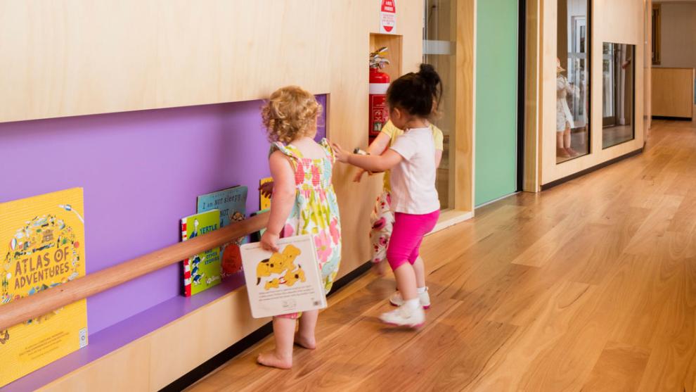 Two children standing in the hallway holding books from the bookshelf