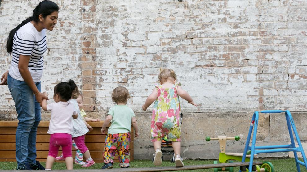 Teacher assisting children with balance beam outside