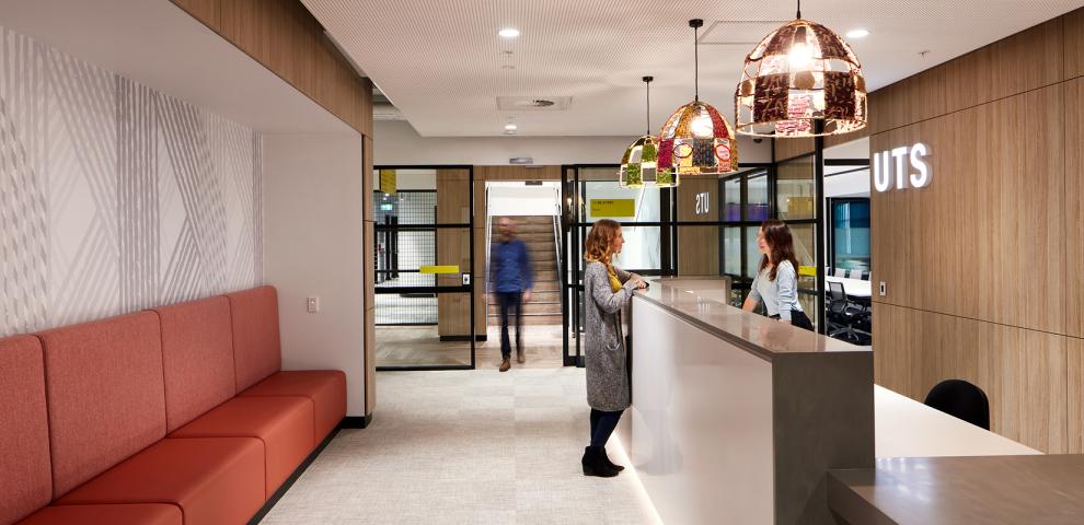 A large reception area features geometric wall art and woven light fittings