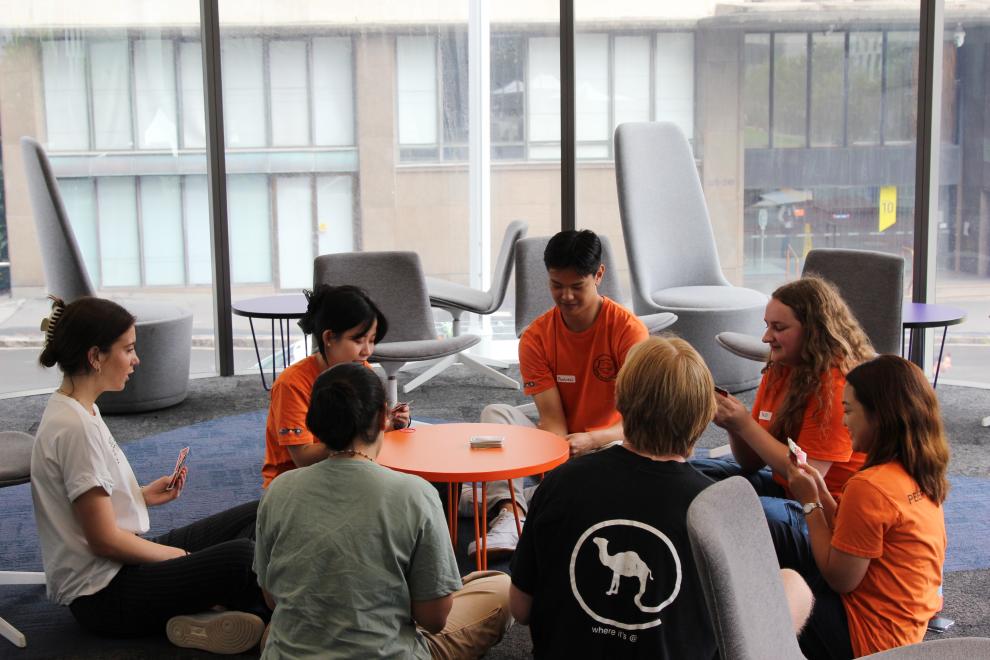 Four Peer Networkers playing cards with students. 