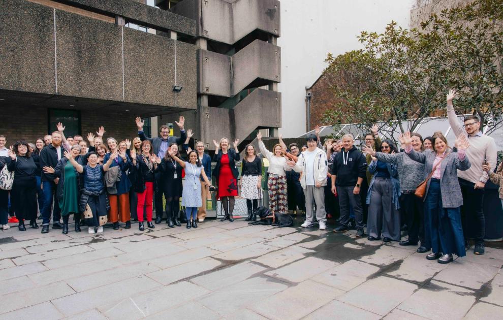 A group of people outside UTS building 1, their hands are in the air in celebration