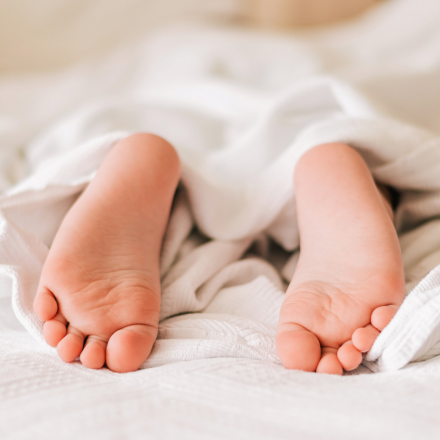 A picture of a child's feet covered in blanket as if the child is sleeping on a bed