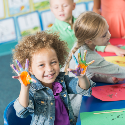 Child in day care with painted hands.