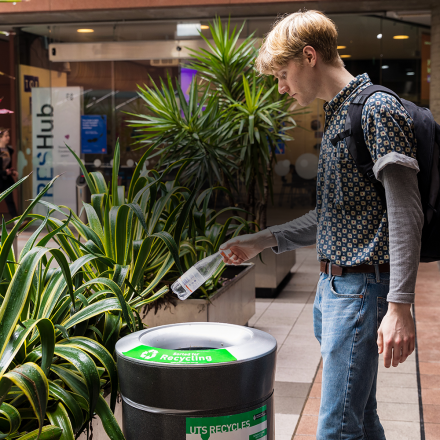 Student placing bottle in recycling bin at UTS