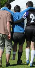 Injured player being helped off the pitch.