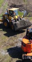 Two construction vehicles on a dirt road, highlighting the machinery used in construction activities in a rugged environment.