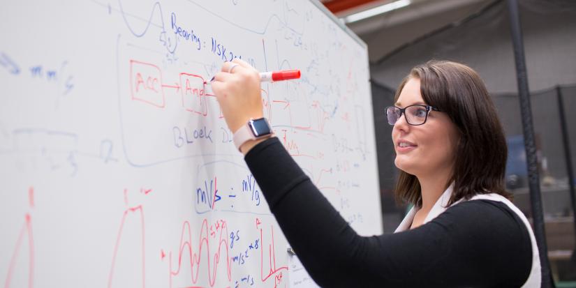 Female postgraduate writing equations on a whiteboard