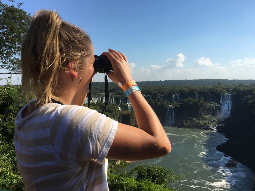 Alana looking through binoculars at a waterfall