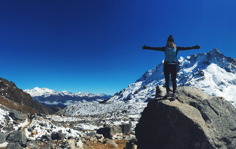FASS Argentina ICS study tour Alana standing on a snowy mountain under blue skies with arms outstretched
