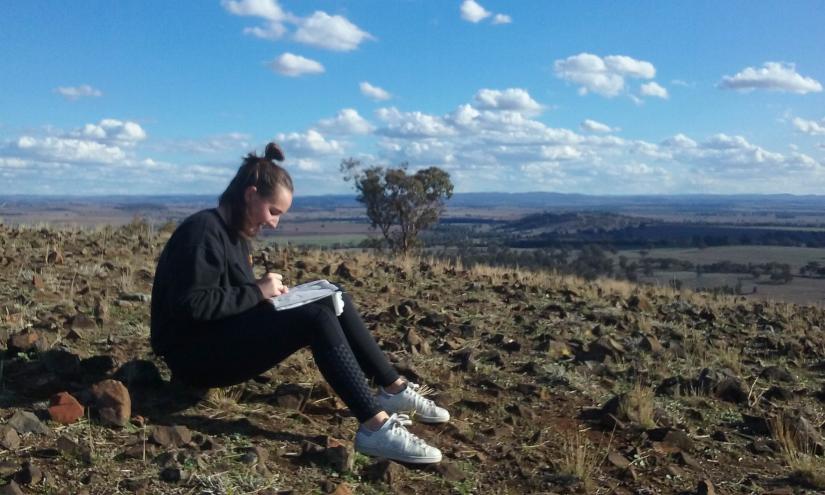UTS Interior Architecture student sits drawing in regional landscape