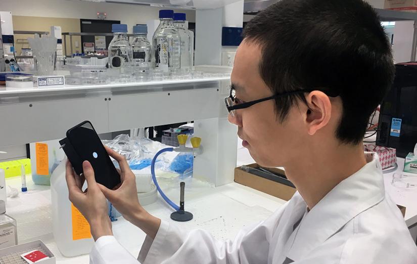 Hao He holding his mobile phone cancer test prototype