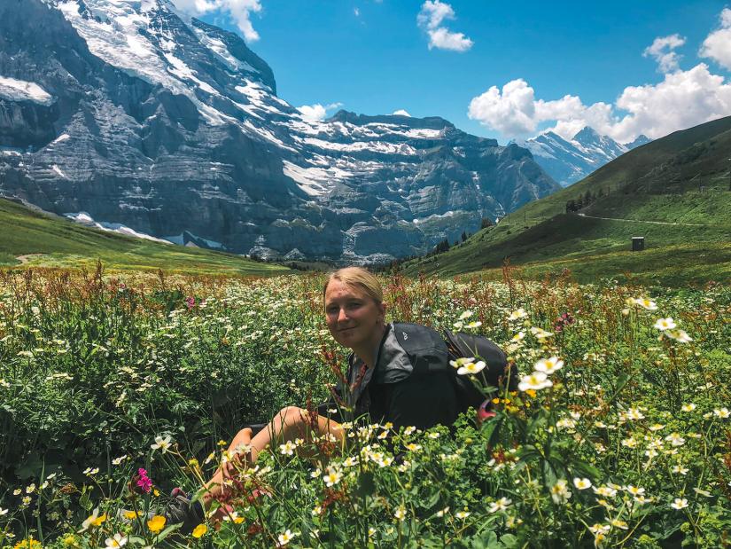 FASS ICS Switzerland study tour Kristen sitting in a field in front of beautiful mountain scenery