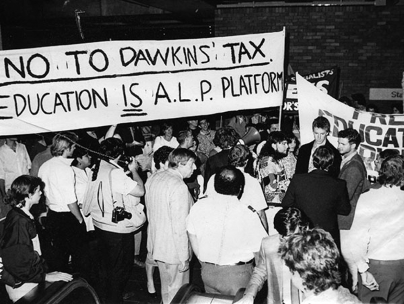 Crowd of people holding a sign \"No to Dawkins tax\"