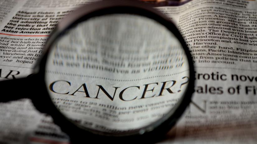 Magnifying glass focusing on the word 'cancer' in a newspaper. Image by PDPics from Pixabay