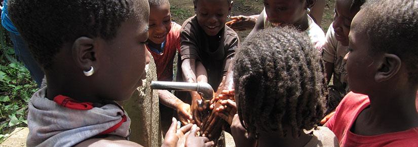 Children in Haiti wash their hands at a water spout during a cholera vaccination campaign.