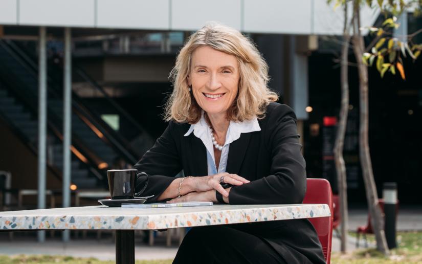 Professor Suzanne Chambers AO, Dean of the Faculty of Health at UTS, sits at a table smiling.