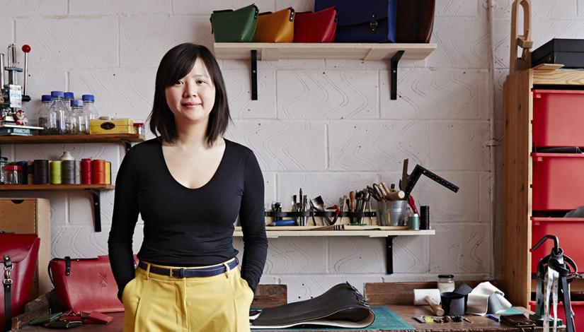 Candice Lau in her workshop surrounded by tools and finished bags.